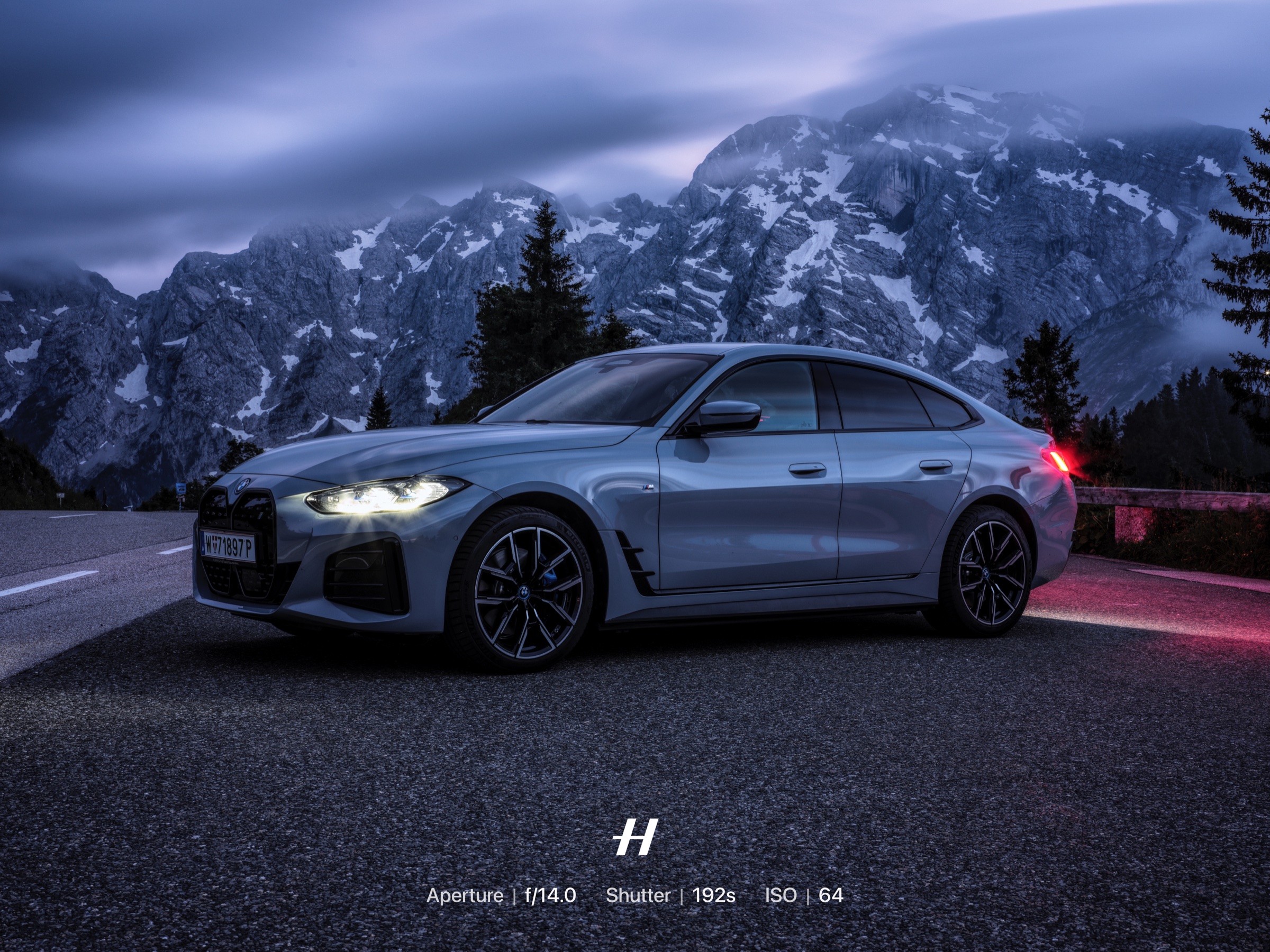 Front wheel detail of a blue BMW i4 against an Alpine landscape